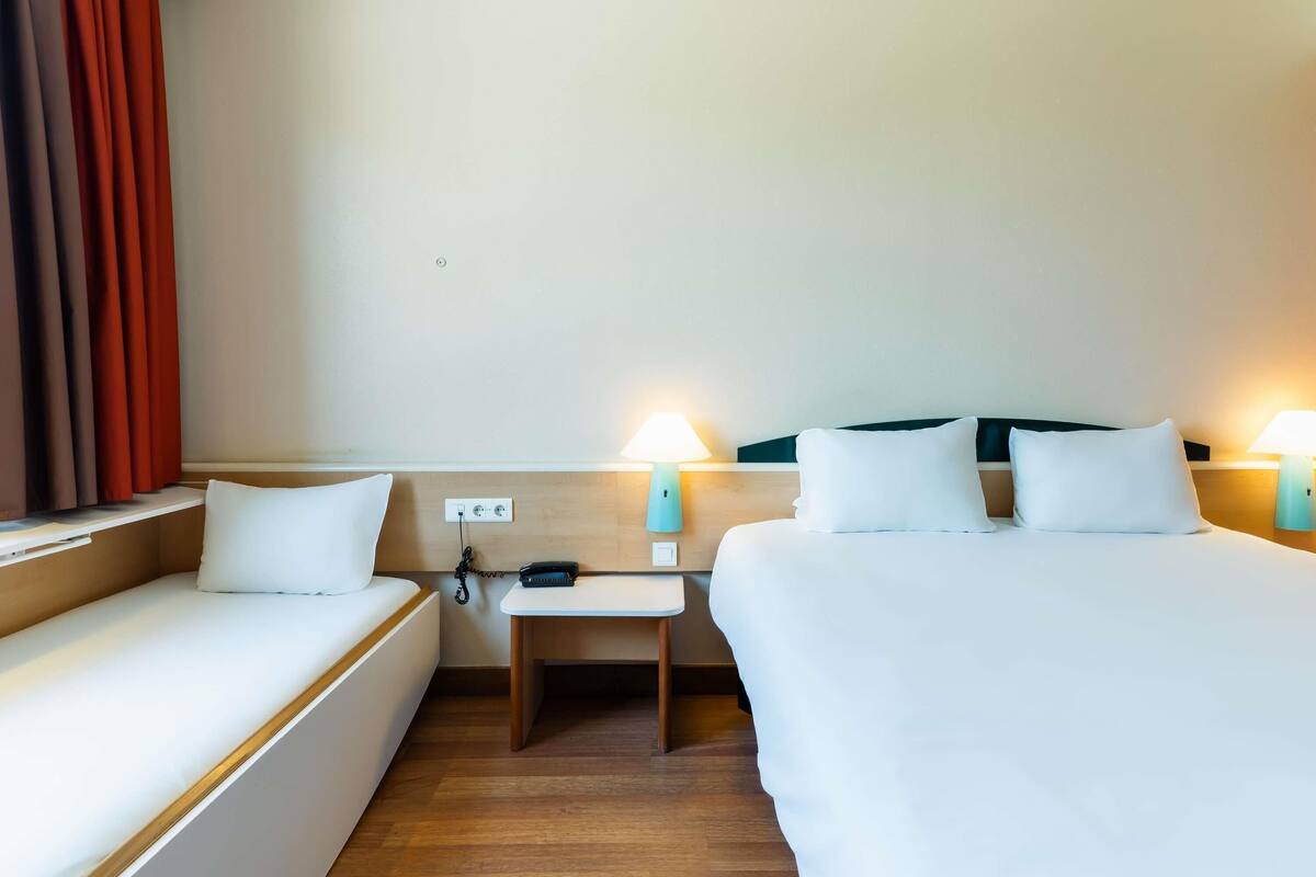 Une chambre d’hôtel avec deux lits, un bureau et un téléphone.