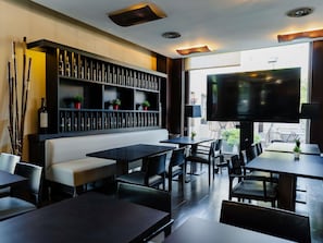 A restaurant interior with tables, chairs, a sofa, a TV, and a wine rack.