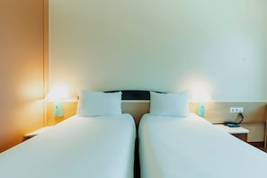 Ein Hotelzimmer mit zwei Betten, Nachttischlampen, einem Nachttisch und einer Steckdose.