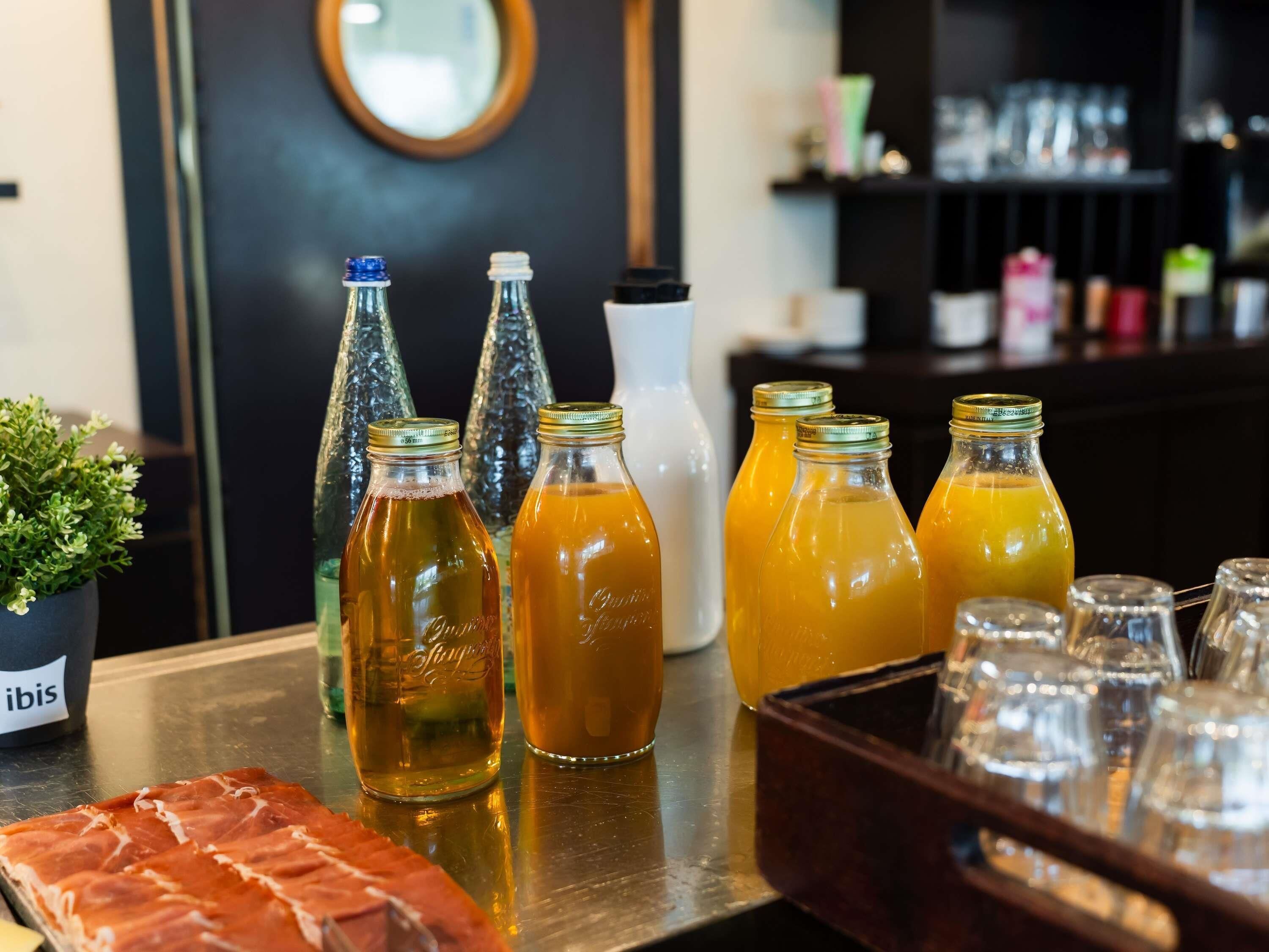 A bar area with bottles of drinks, a potted plant, and a tray of food.