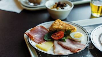 A plate with various food items including ham, cheese, a boiled egg, and a slice of bread.