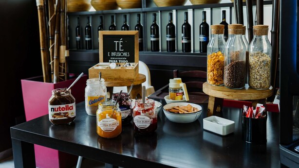 Una zona de bar con botellas, frascos de condimentos y un letrero de madera.