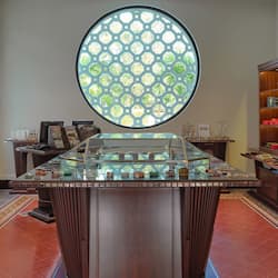 Jewelry store interior with a central display case and surrounding shelves and cabinets showcasing a variety of items.
