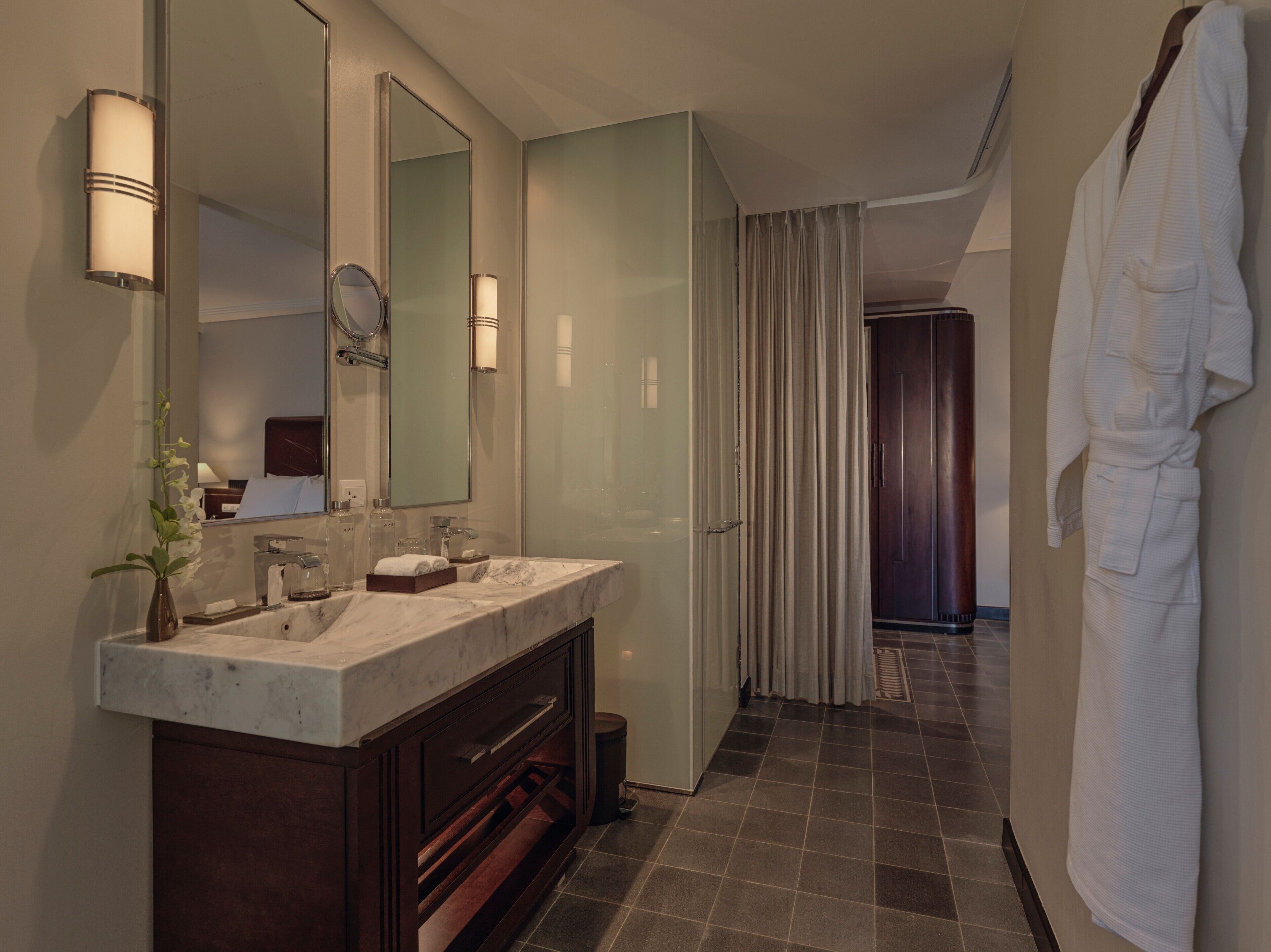 Une salle de bain moderne avec un meuble-lavabo à deux vasques, un grand miroir et un peignoir accroché au mur.