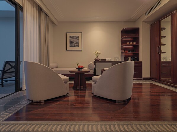 A modern living room with a sofa, two armchairs, a coffee table, and a bookshelf.