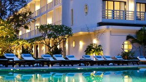 A hotel with a pool, lounge chairs, and a reflection of the building in the water. - Azerai La Residence Hue (Hue)