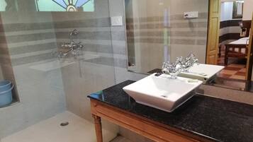Een moderne badkamer met een douchecabine van glas, een wastafel met twee wasbakken en een houten tafeltje.
