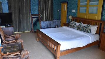 Un dormitorio con una cama grande, cabecera de madera y televisor sobre un mueble de madera.