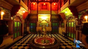 A traditional interior with a checkered floor, a central fountain, and ornate wooden balconies. - Krishna Prakash Heritage Haveli (Jodhpur)
