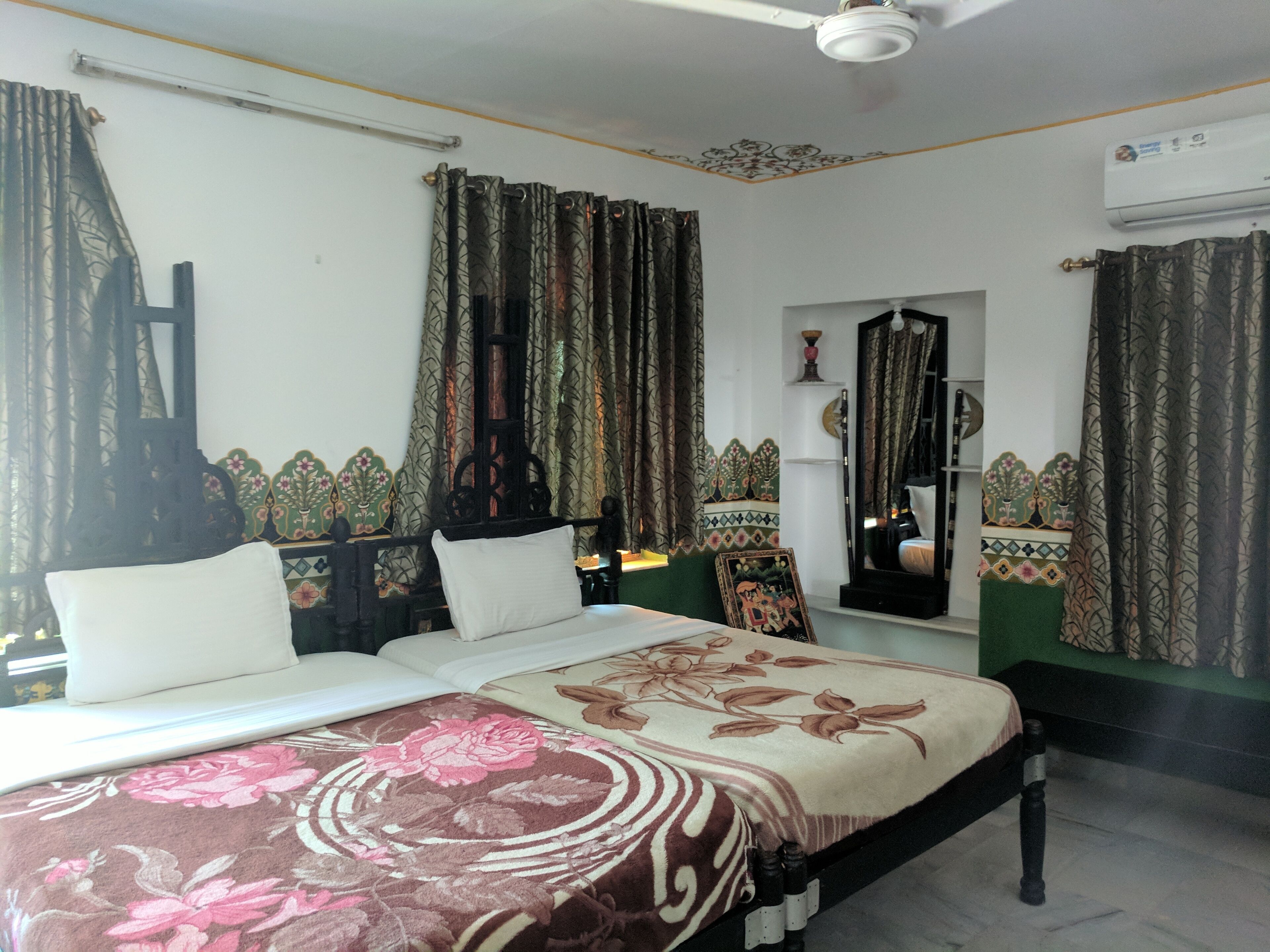 Un dormitorio con cama, cortinas, ventilador de techo y espejo.