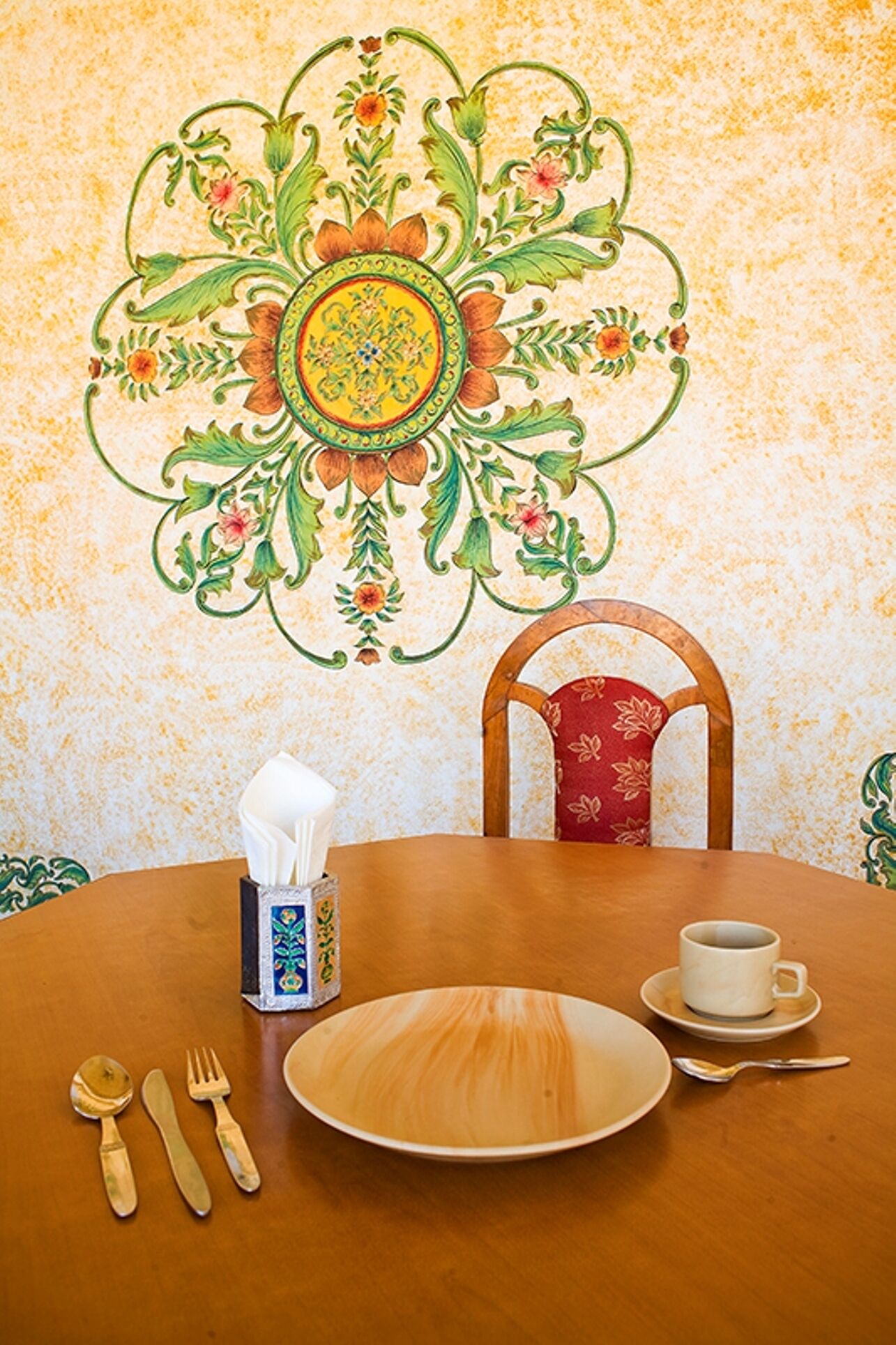 A dining table set with a tissue box, a cup, and cutlery.