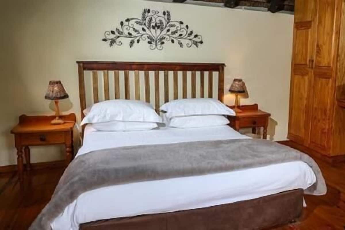 A bedroom with a wooden bed, two bedside tables with lamps, a wooden wardrobe, and a decorative wall piece.
