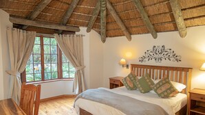 Une chambre à coucher avec un lit en bois, une table de chevet, une table et une fenêtre avec des rideaux.