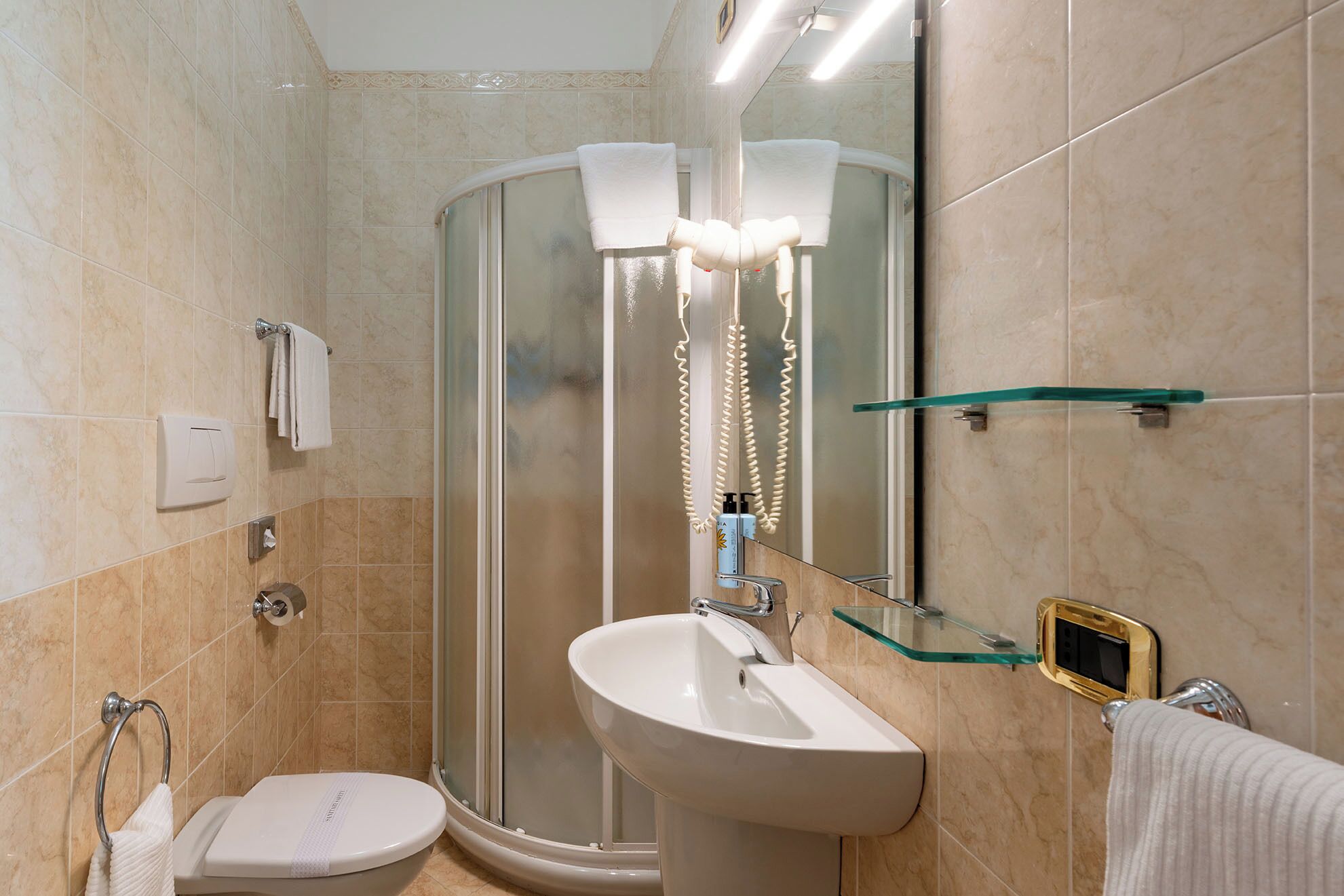 A bathroom with a glass shower enclosure, a white sink, and a toilet.