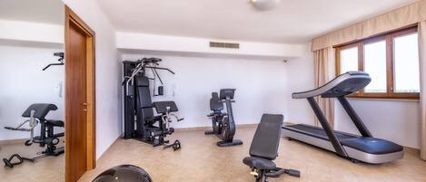 A gym with exercise equipment including a treadmill, stationary bikes, and a rowing machine.