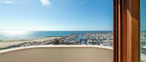 A balcony with a view of a marina and beach.