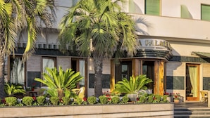 Een hotel met een palmboom en een bord waarop 'Palace Hotel' staat.