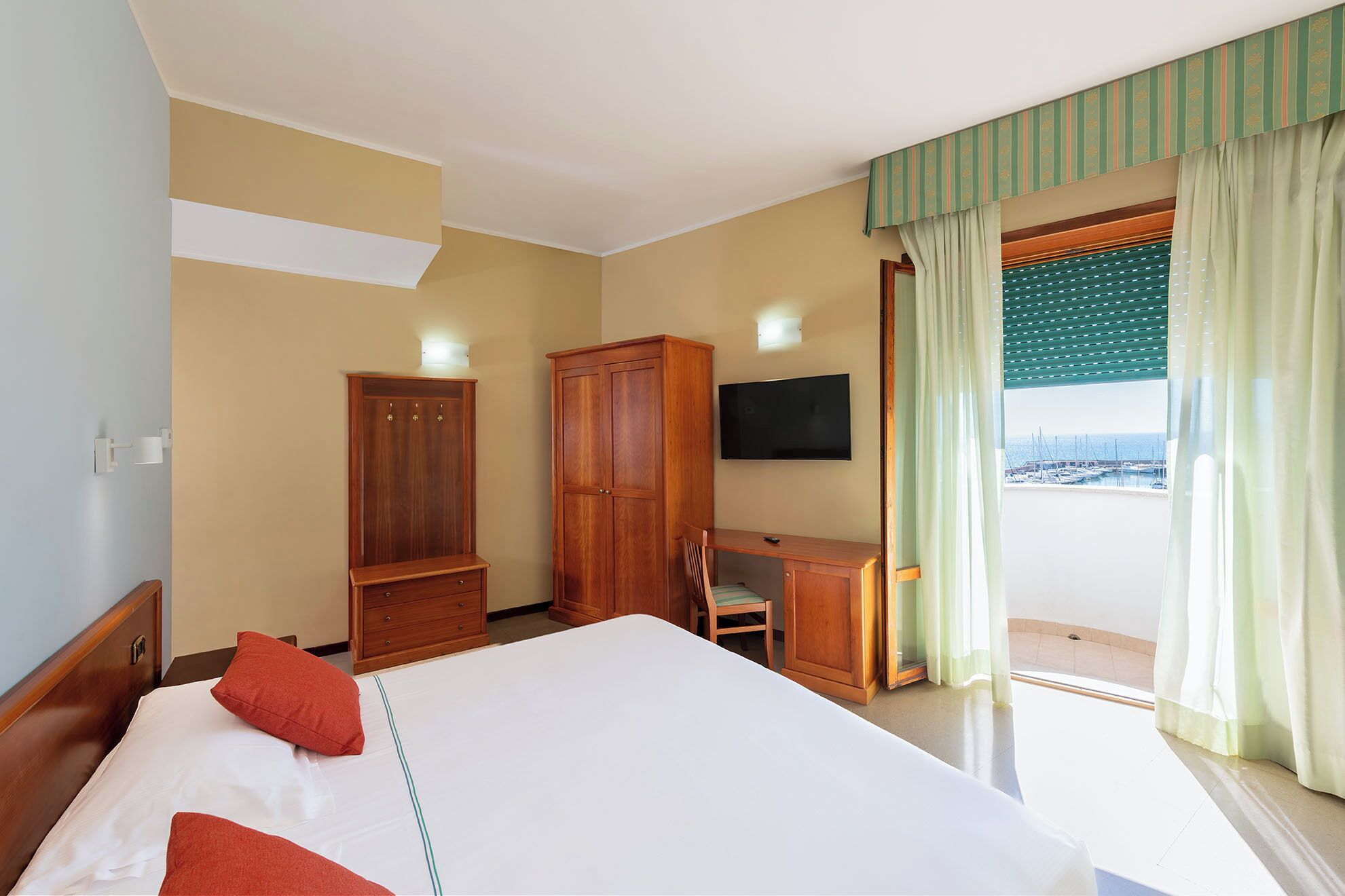 Habitación de hotel con cama, escritorio, televisión y vistas al mar.