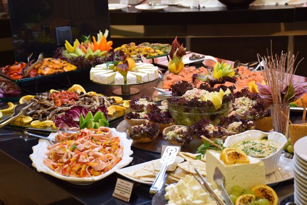Un bufé con diversos platos, incluyendo mariscos, ensaladas y quesos.