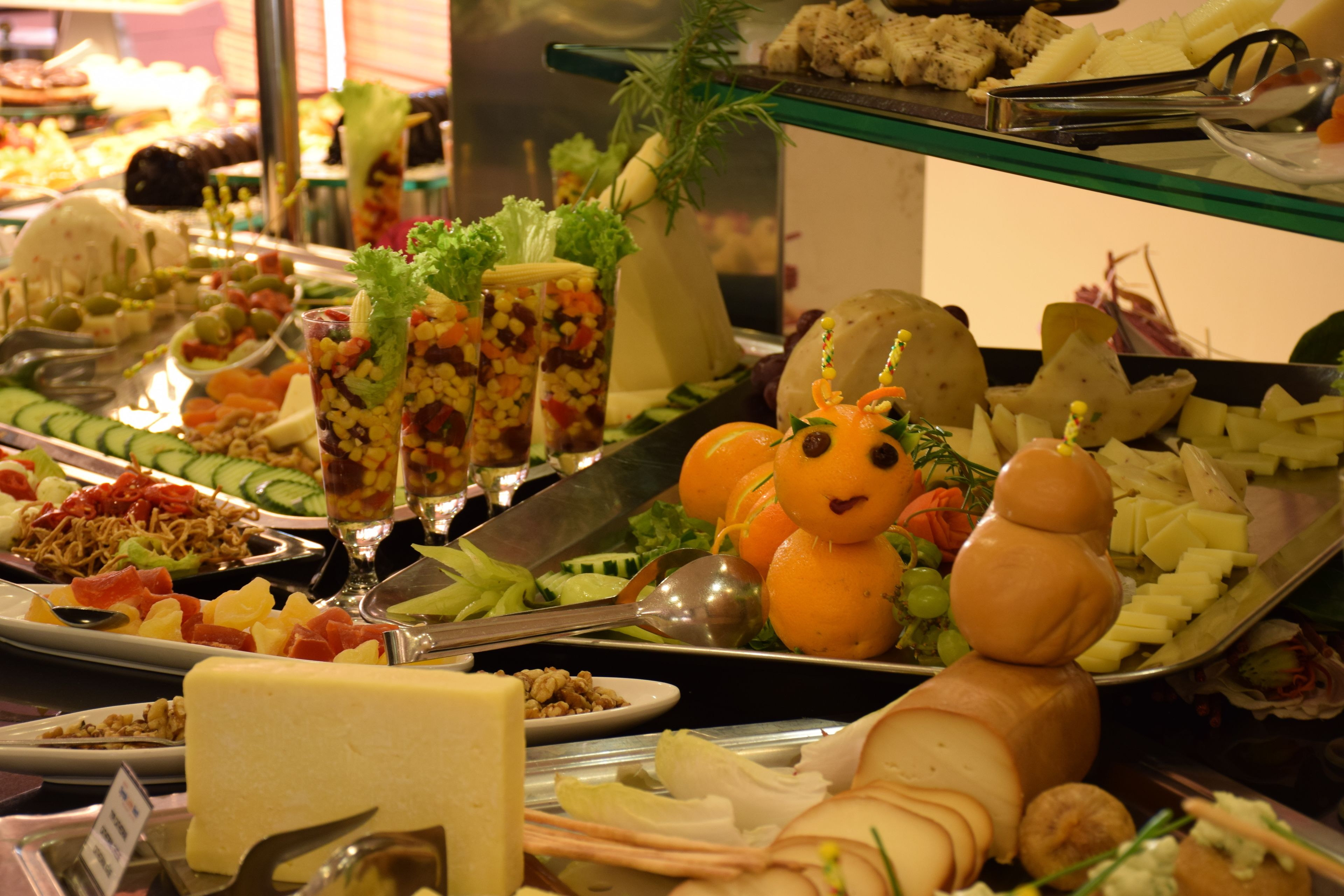 Een buffet met diverse gerechten, zoals fruit, groenten, kazen en vlees.