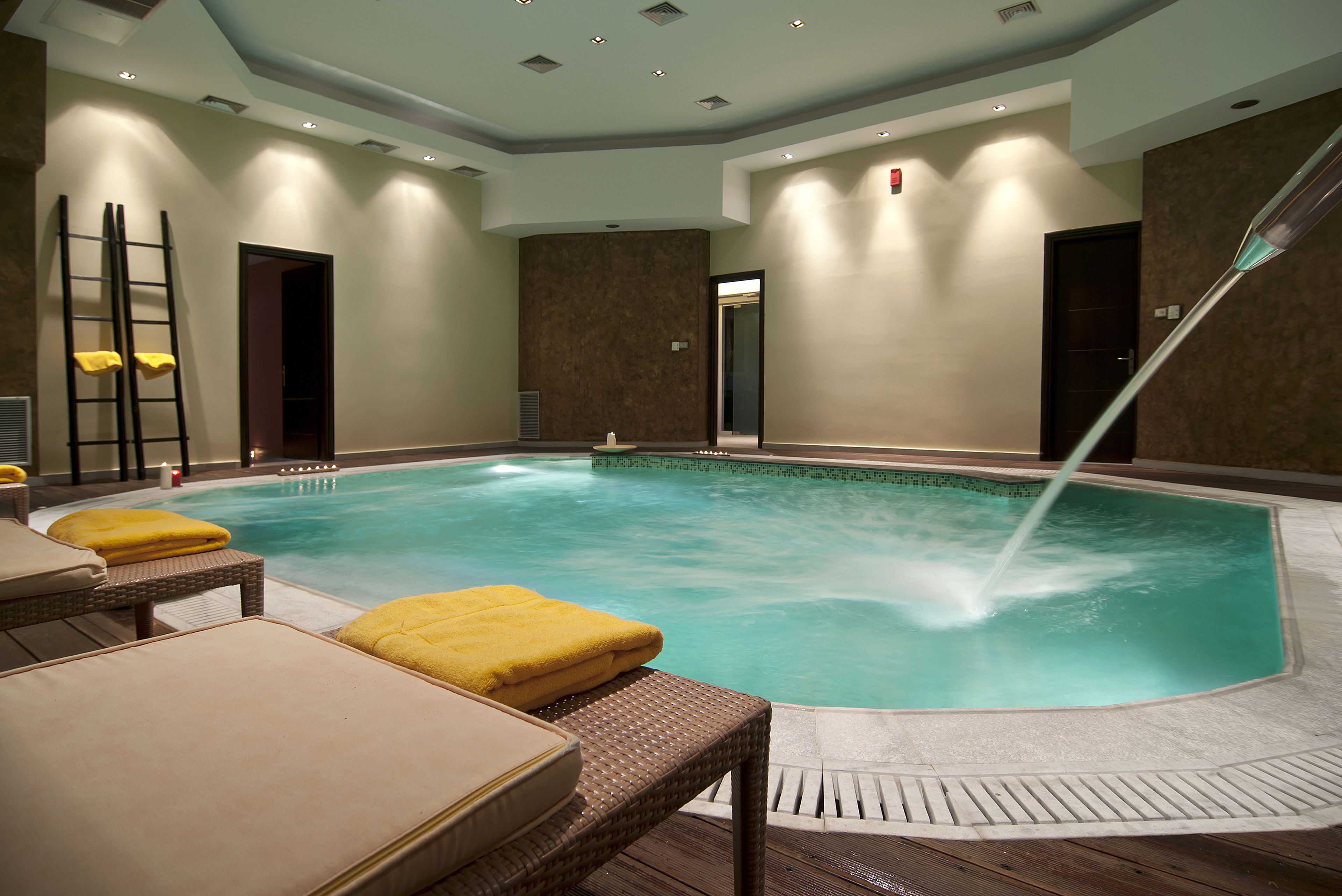Un área de spa con piscina, sillas de descanso y una fuente de agua.