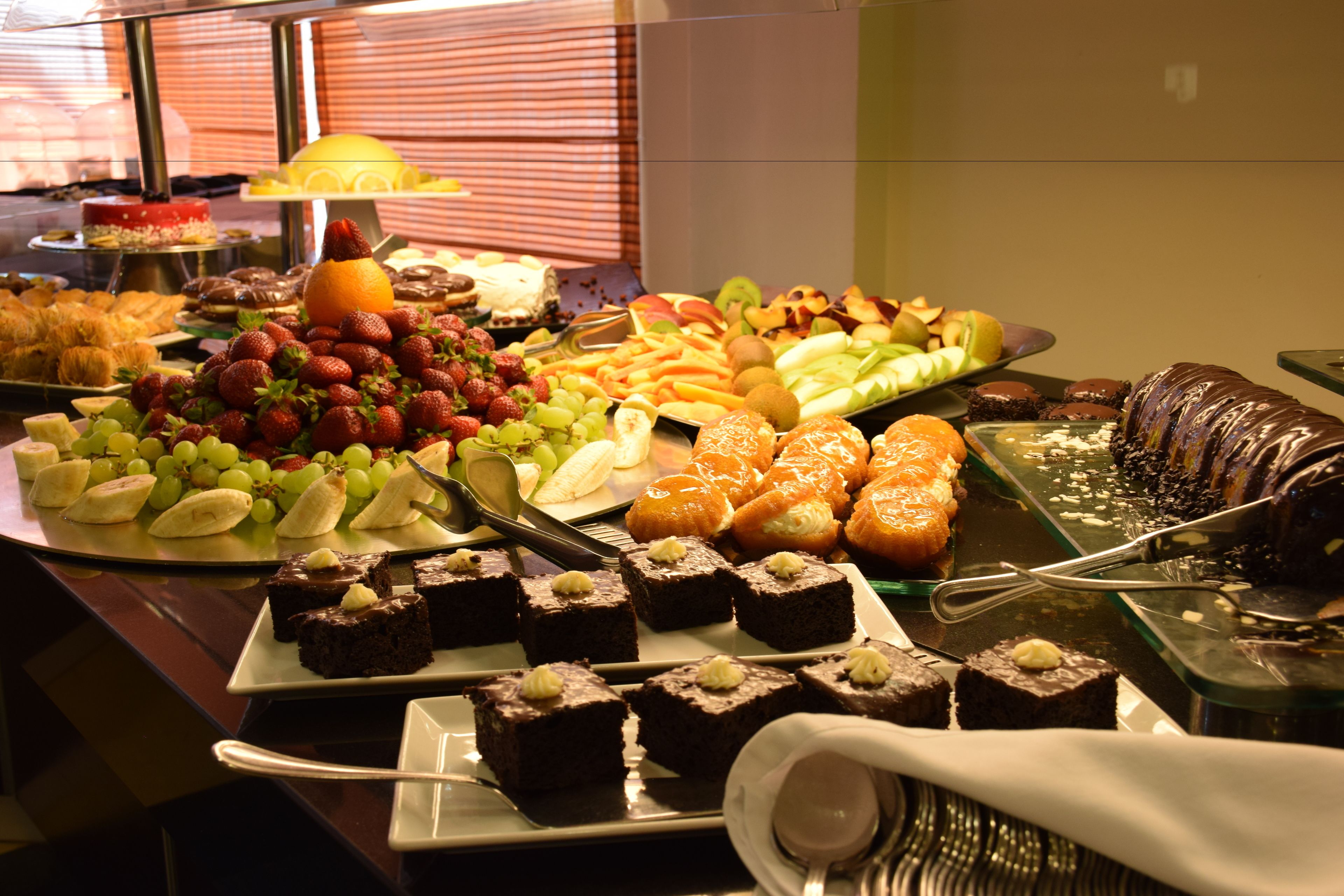 A buffet with various food items including fruits, pastries, and desserts.