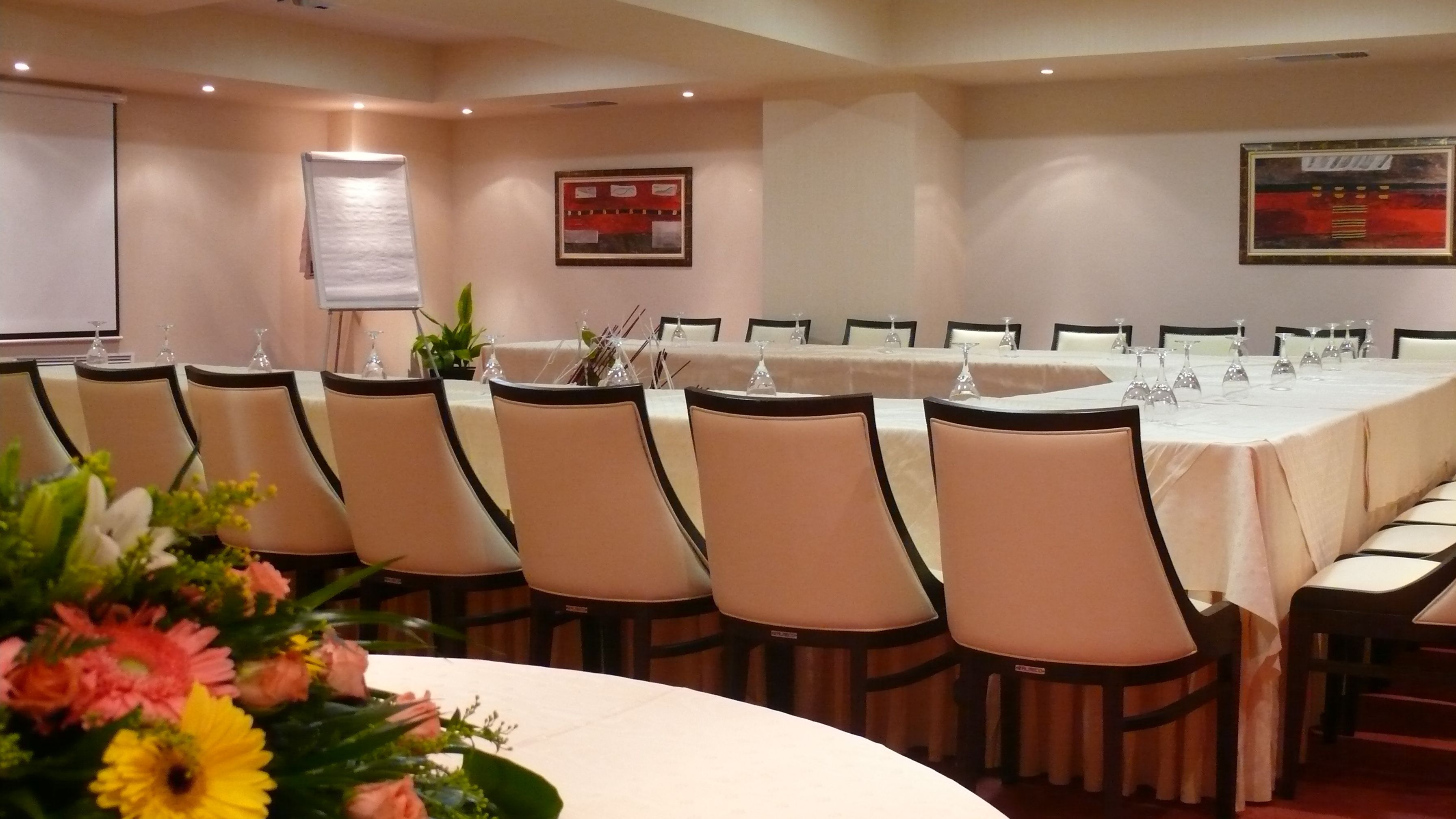 A conference room with a long table, chairs, and a projector screen.