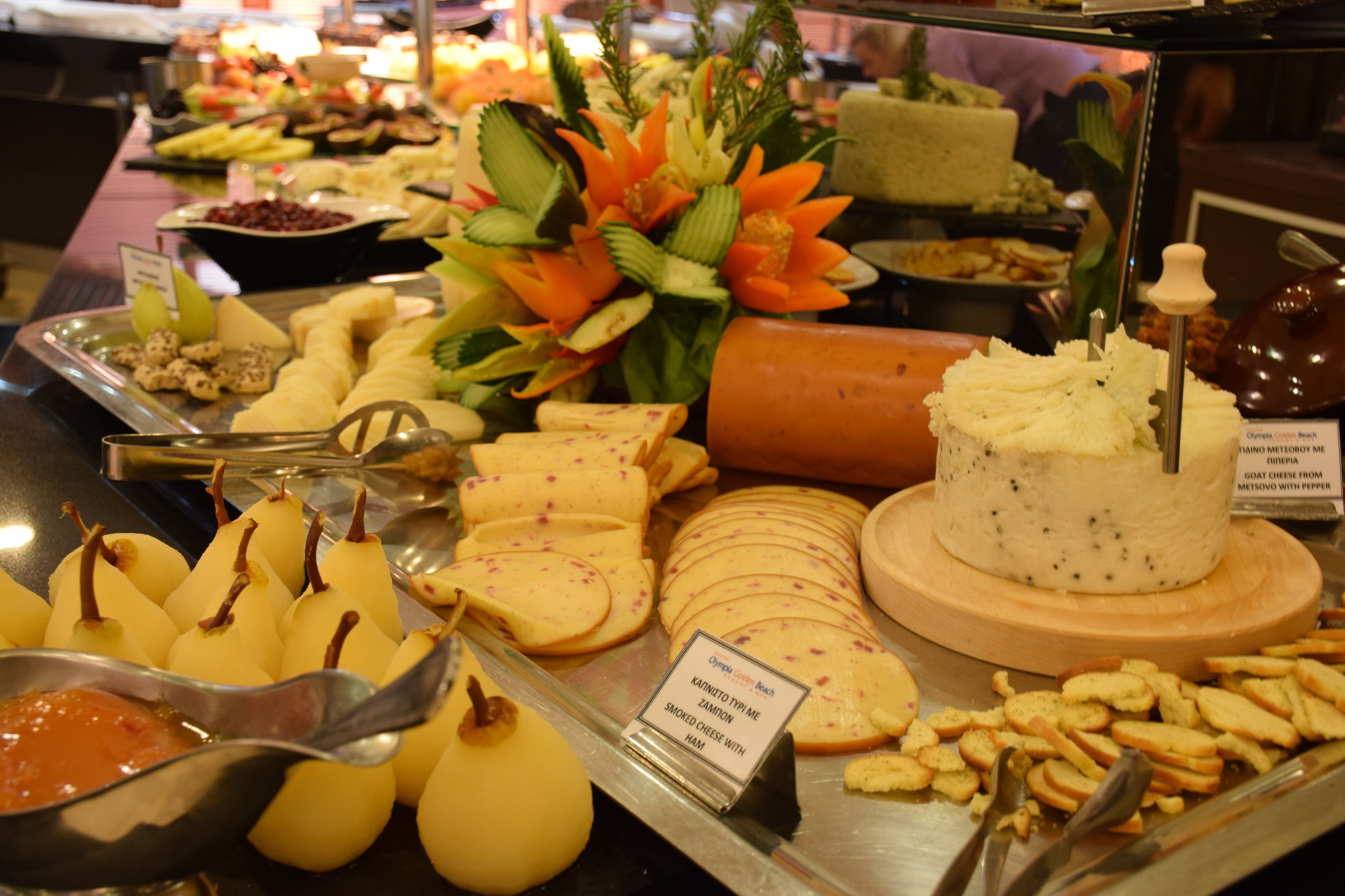 A buffet with various cheeses, fruits, and a decorative centerpiece.