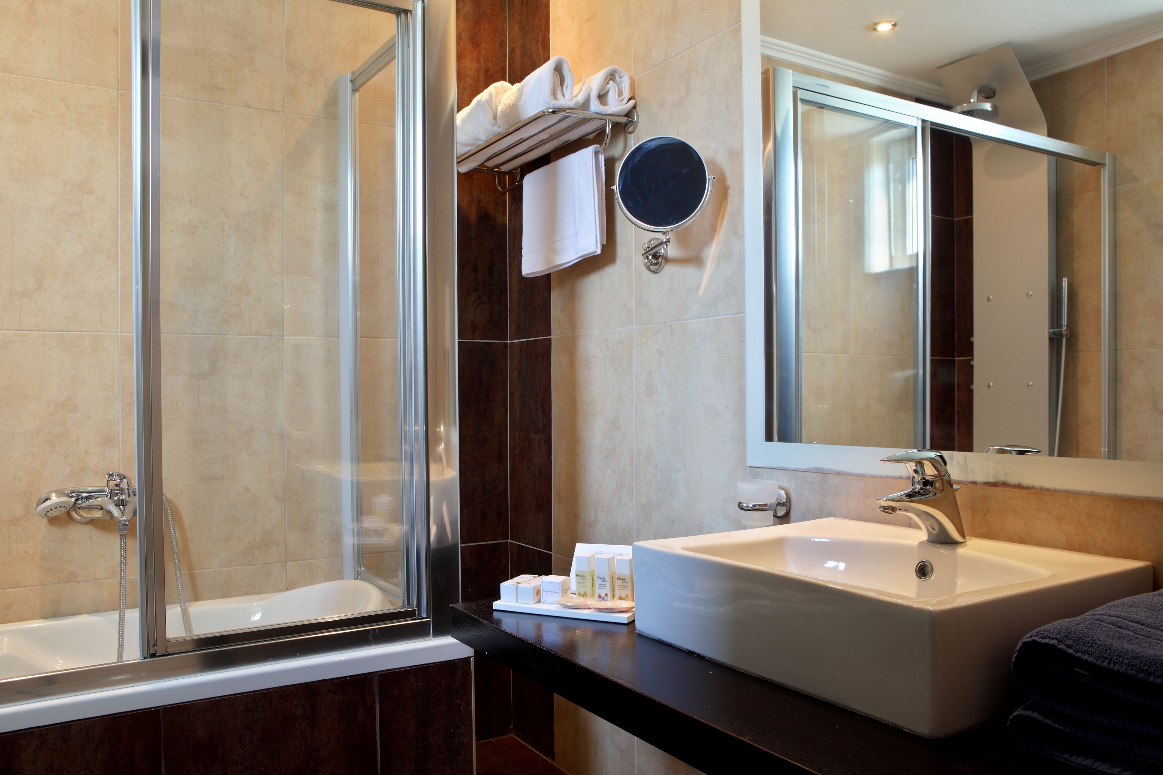 A modern bathroom with a glass-enclosed shower, a large mirror, and a sink with toiletries.