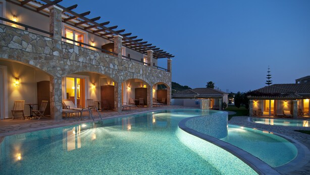 A swimming pool with lounge chairs and a stone building with arched doorways. - Olympia Golden Beach & Spa (Andravida-Kyllini)