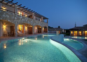 Una piscina con sillas de descanso y un edificio de piedra con puertas de arco.