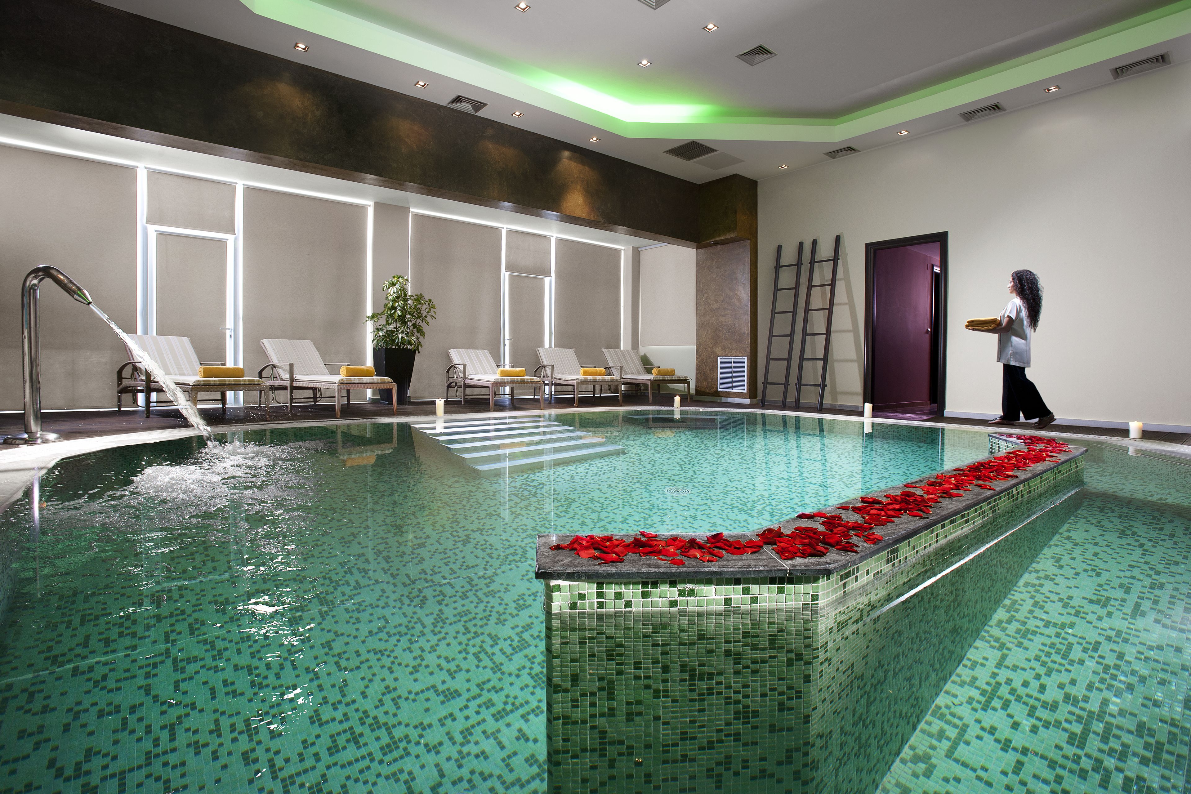A swimming pool with a tiled edge, a ladder, and lounge chairs.