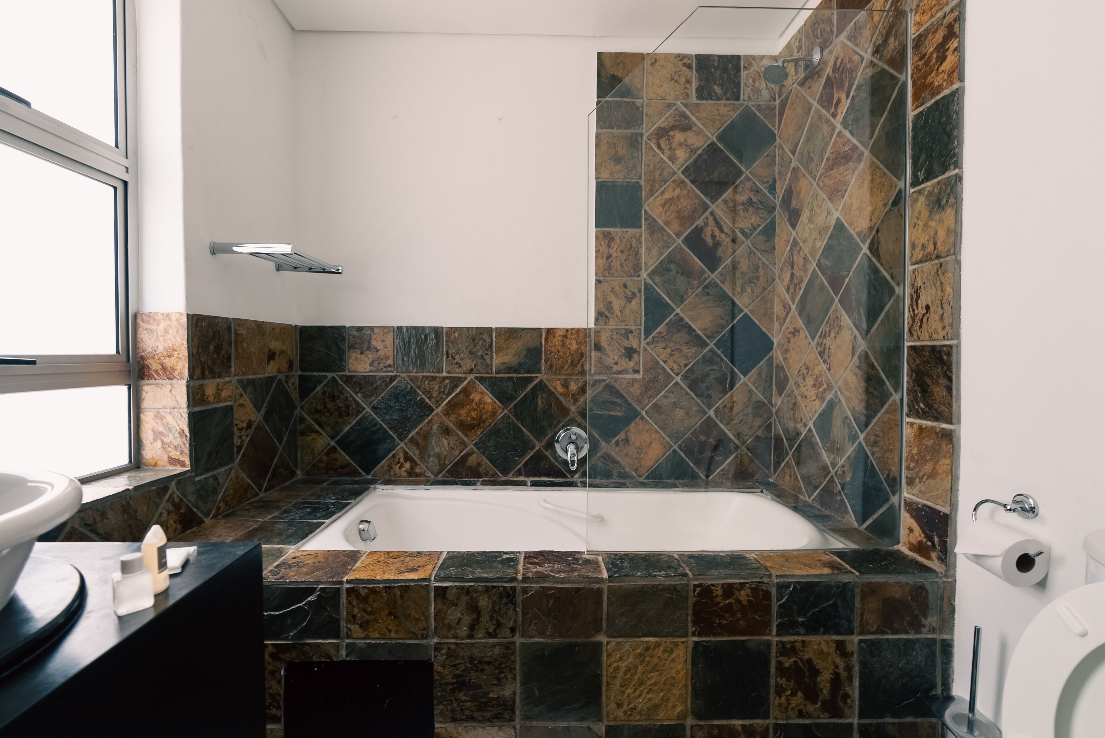 A bathroom with a bathtub, a window, and a toilet.