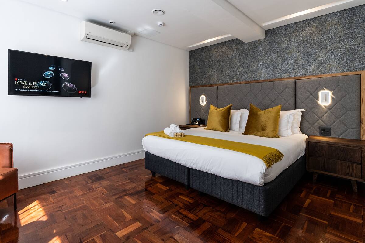 Ein modernes Hotelzimmer mit einem großen Bett, einem wandmontierten Flachbildfernseher und Holzboden.