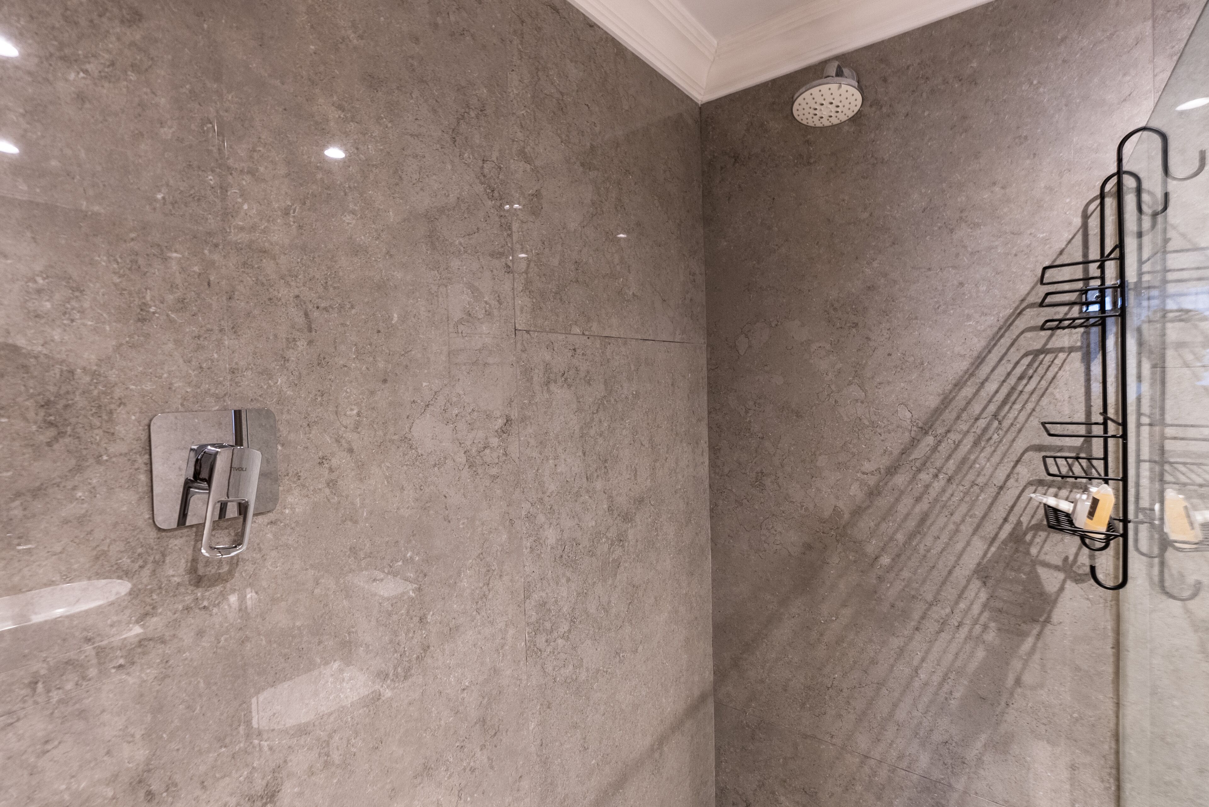 A bathroom with a shower, a towel rack, and a wall-mounted faucet.