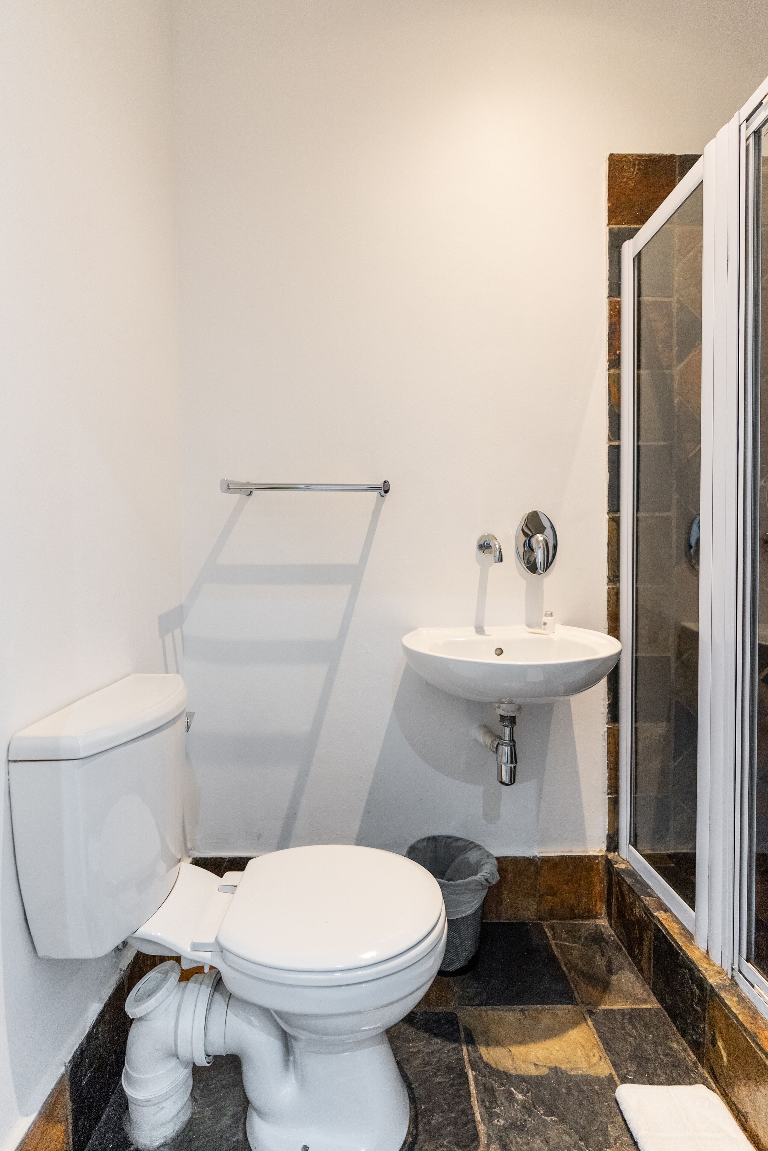 A bathroom with a toilet, sink, and shower area.