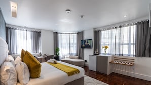 Moderni hotellihuone, jossa on suuri sänky, työpöytä, tuoli ja televisio.