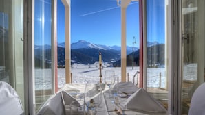 A dining table set for two with a mountain view through large windows. - Schatzalp Snow & Mountain Resort (Davos)