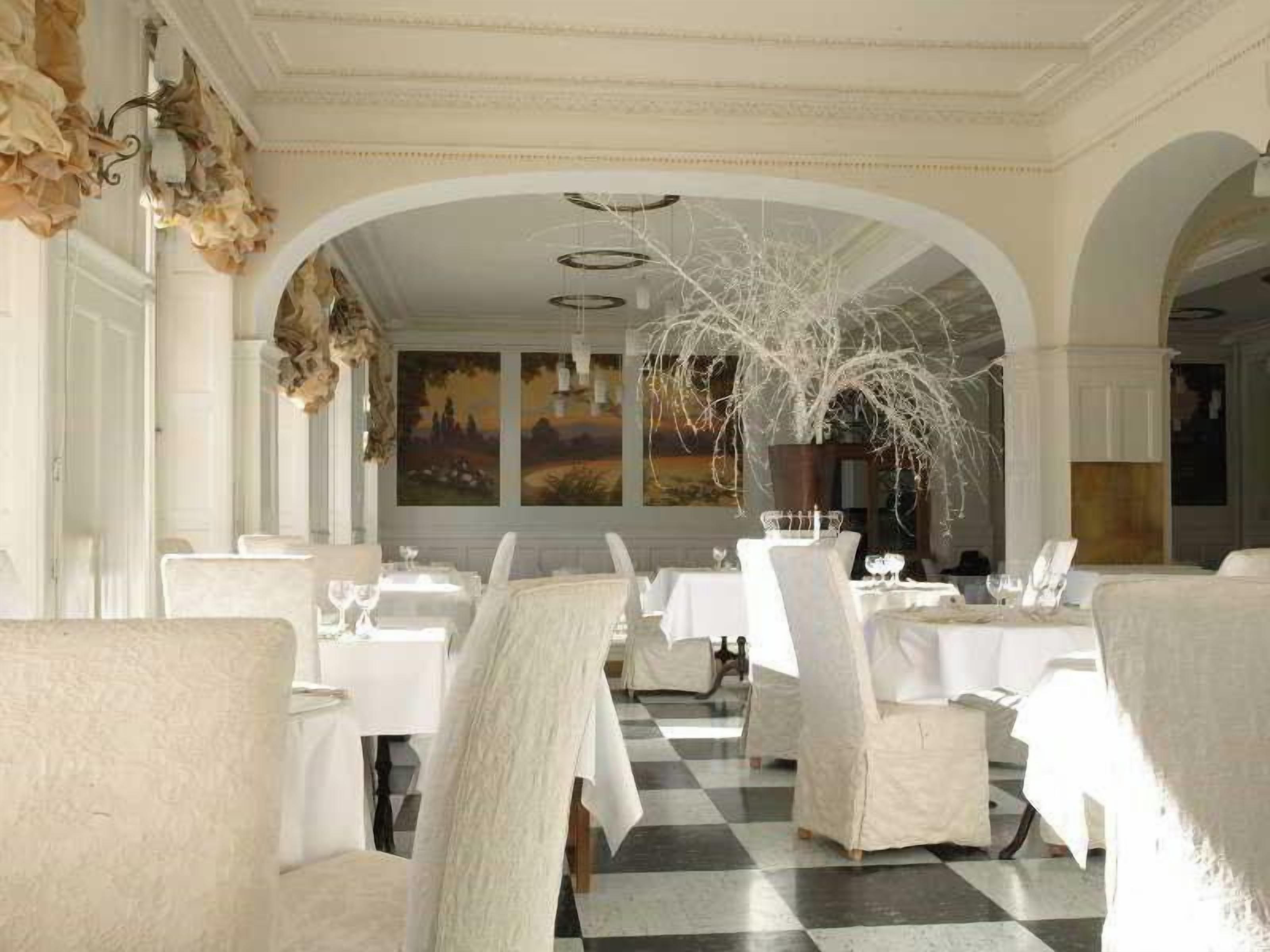 A dining area with tables set for service, white chairs, and a checkered floor.