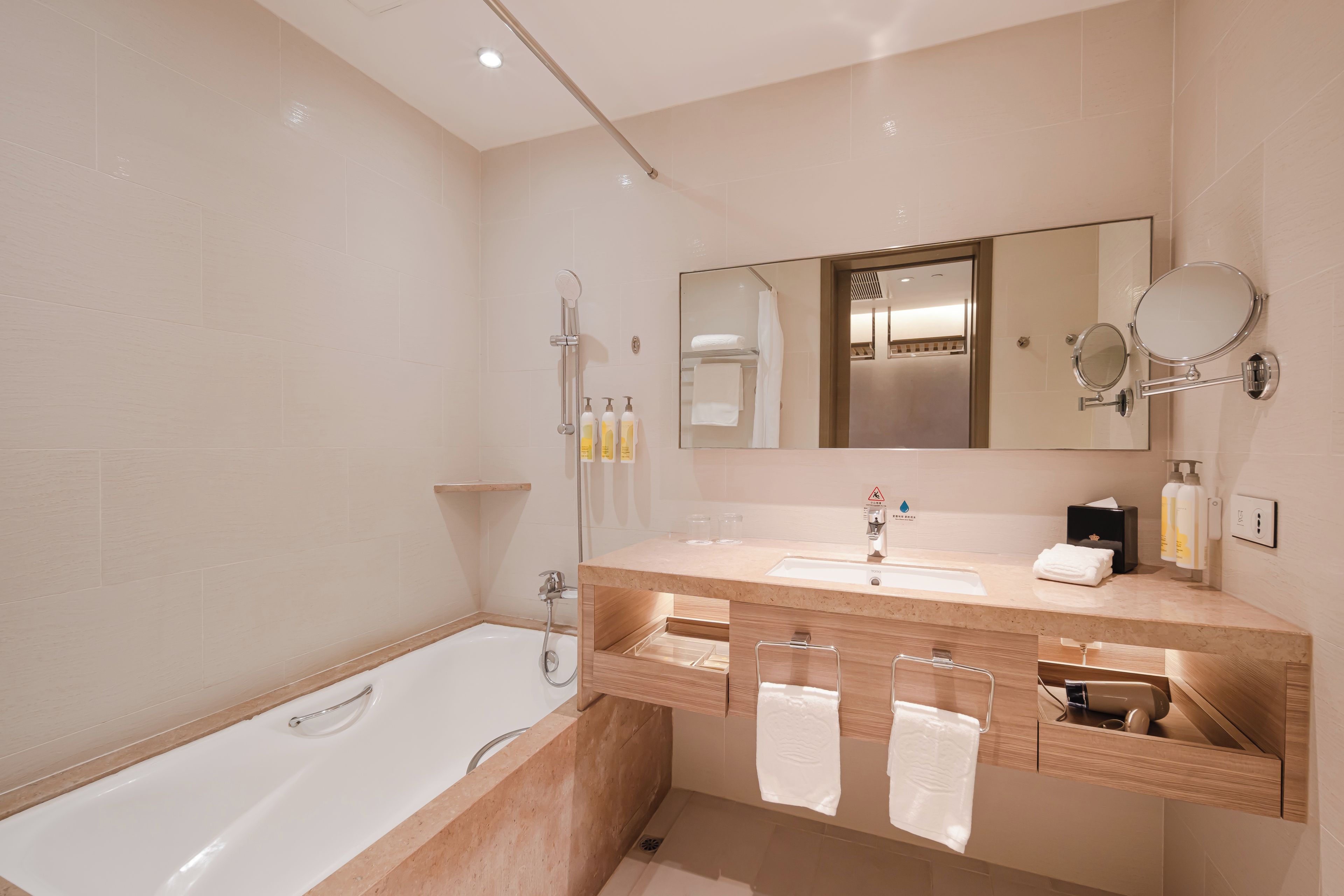 Un baño moderno con bañera, dos lavamanos, un espejo grande y ducha.