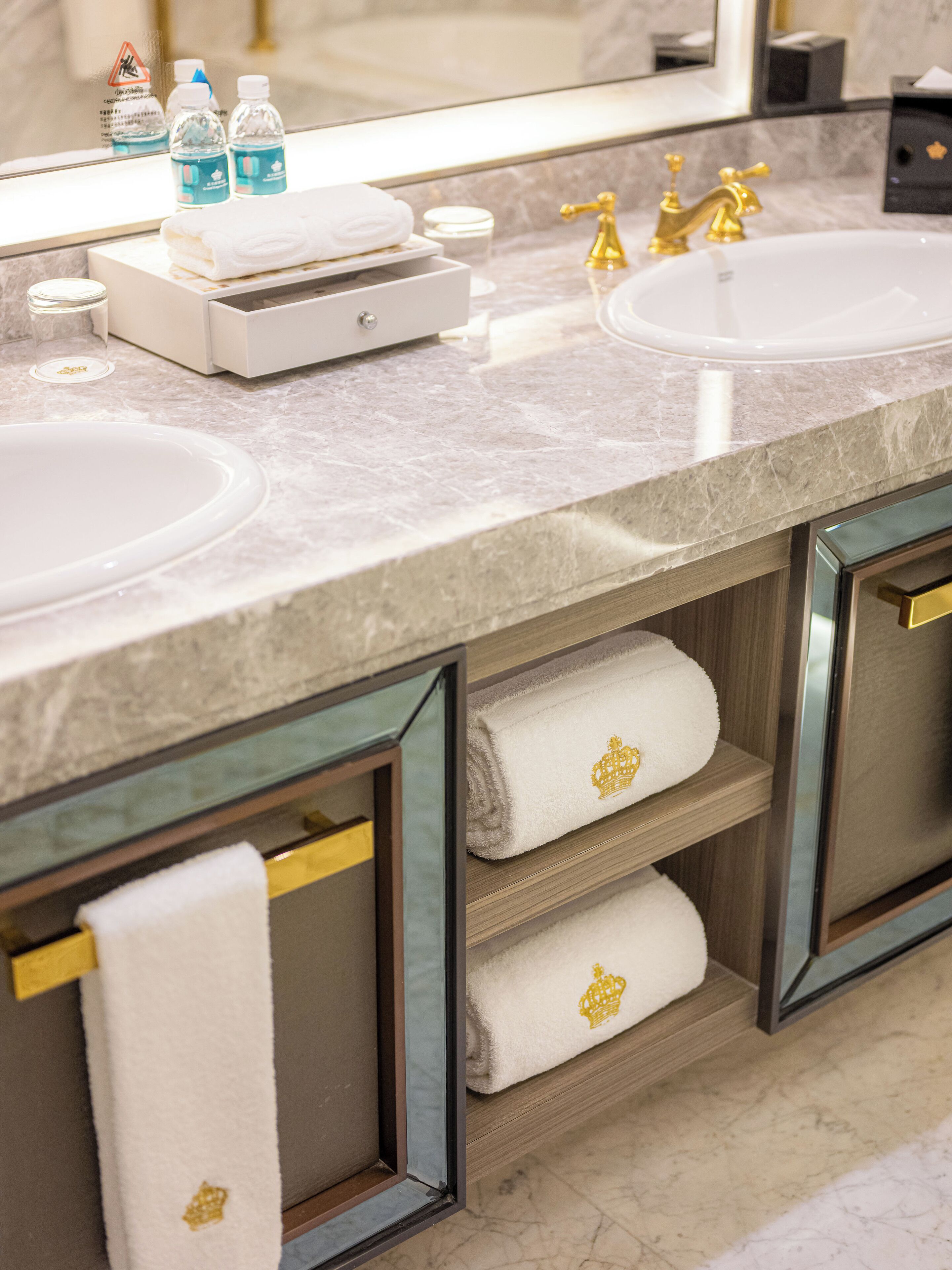 A bathroom with two sinks, a mirror, and shelves with towels.
