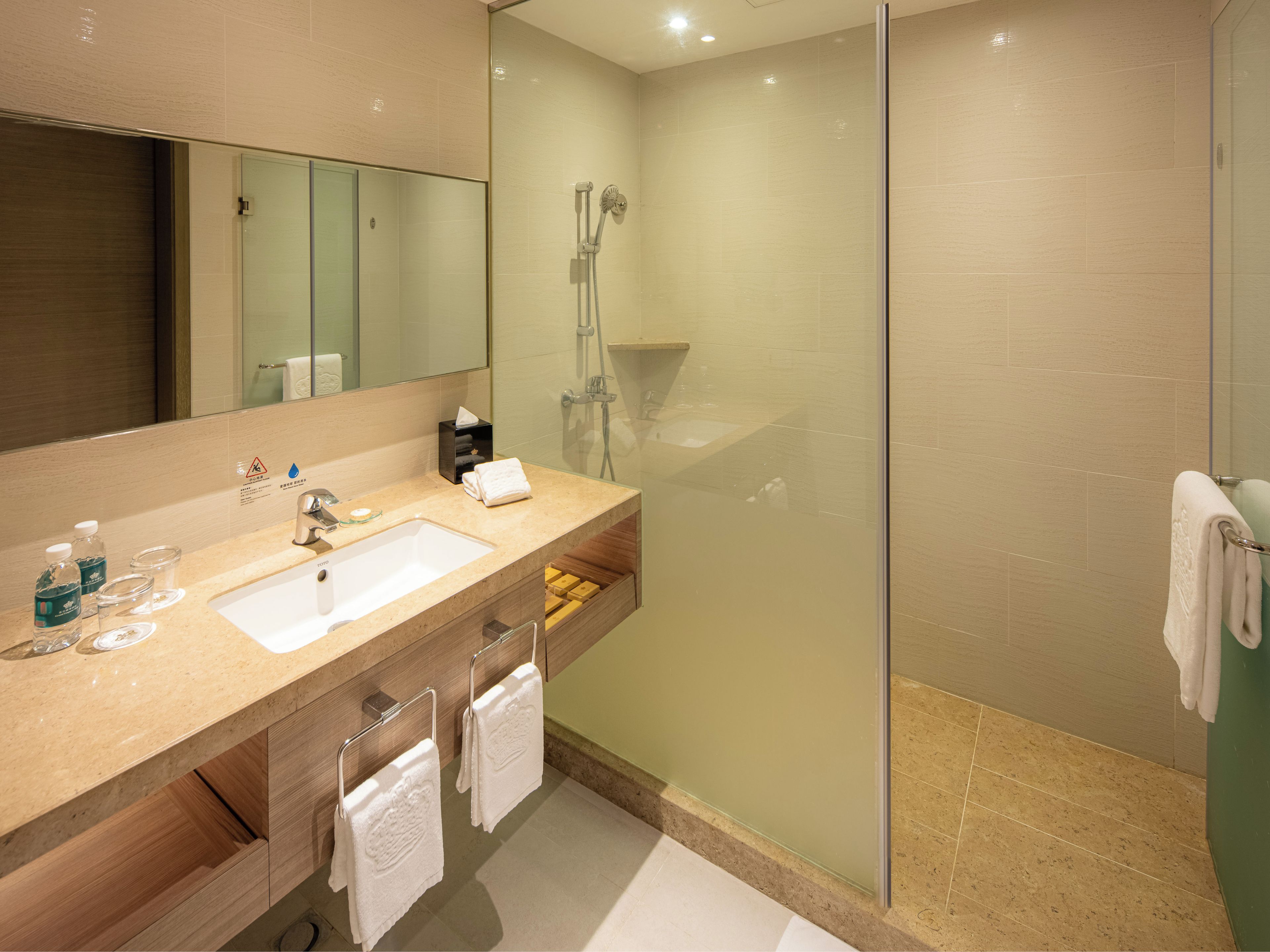 A modern bathroom with a glass-enclosed shower, a sink with a mirror above it, and a wooden vanity.