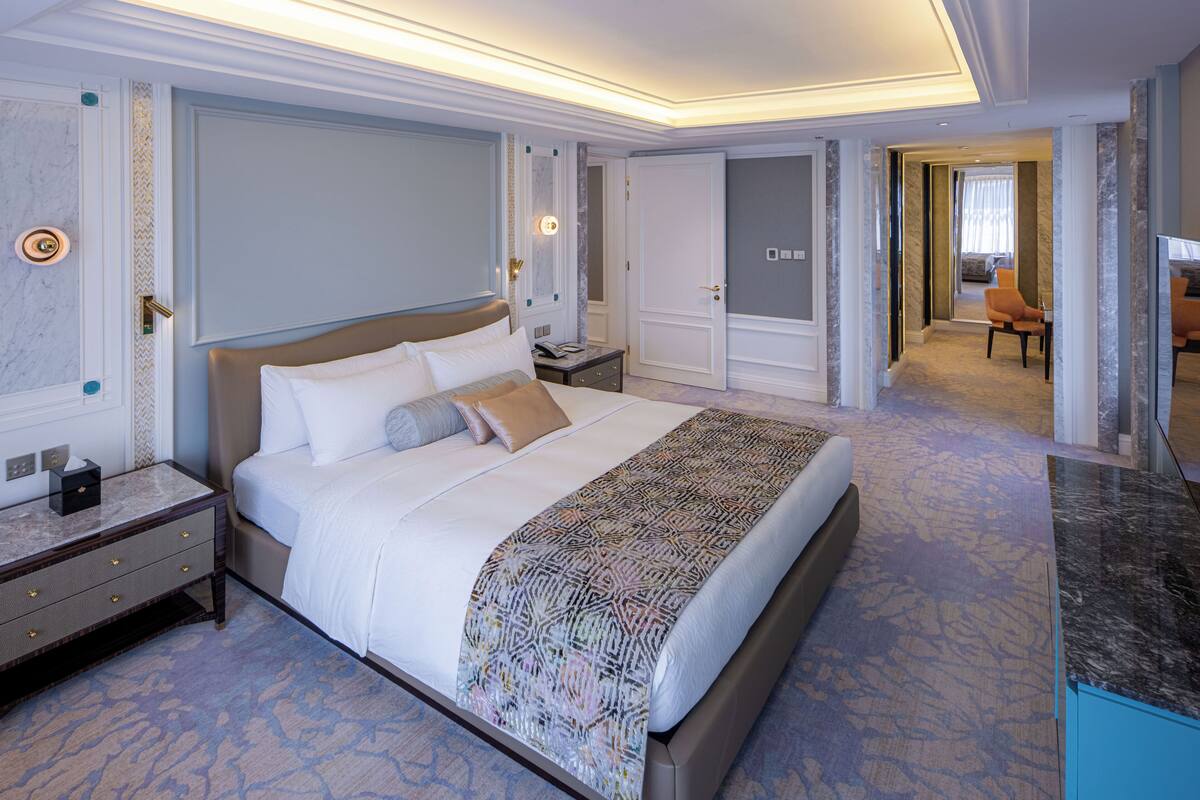 A spacious hotel room with a large bed, a nightstand, a dresser, and a bathroom visible through an open door.
