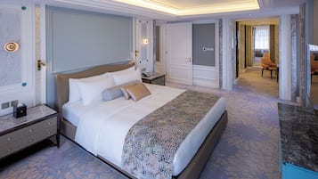 Et rummeligt hotelværelse med en stor seng, et natbord, et kommode og et badeværelse, der kan ses gennem en åben dør.