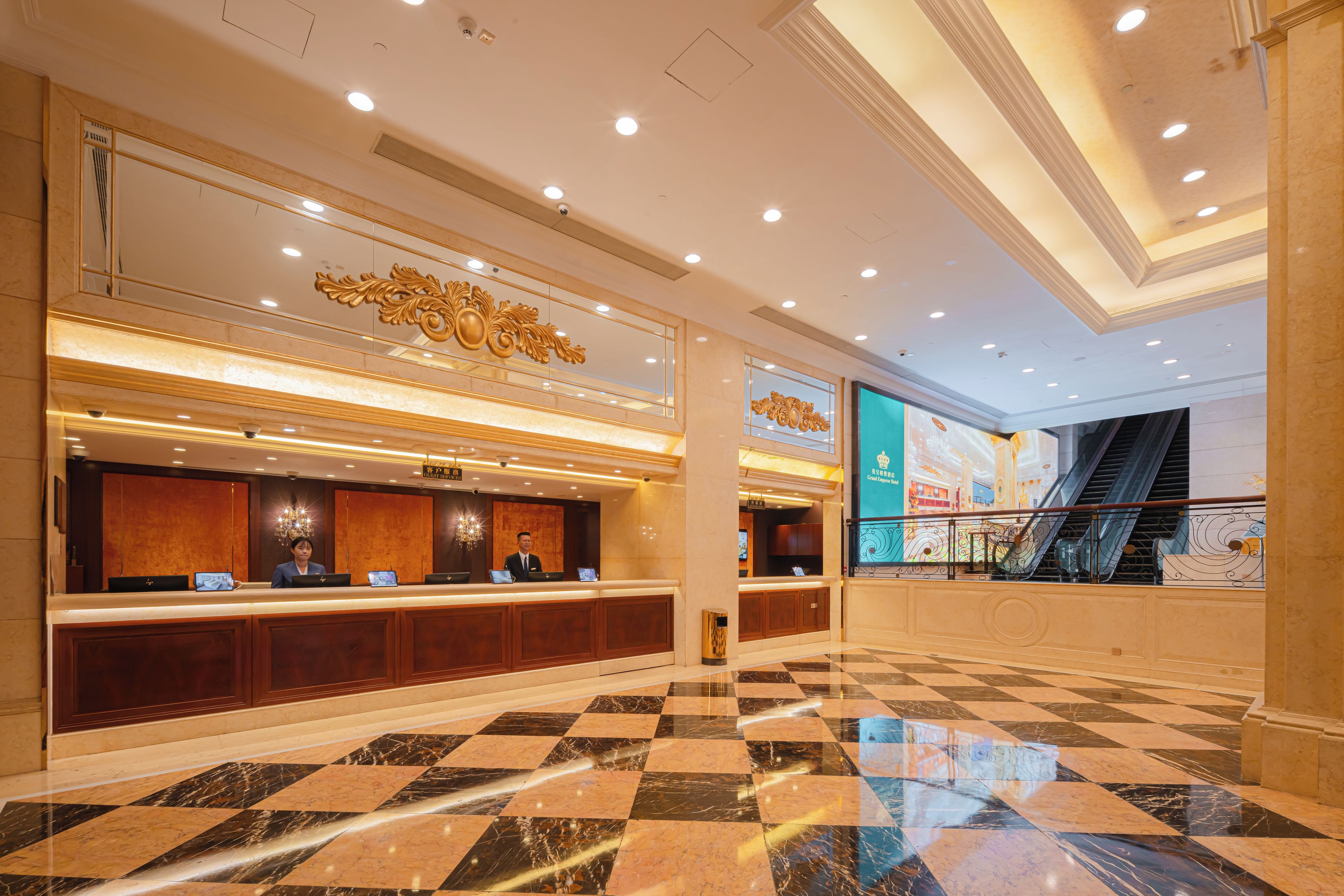 A hotel lobby with a reception desk, check-in counters, and a check-in machine.