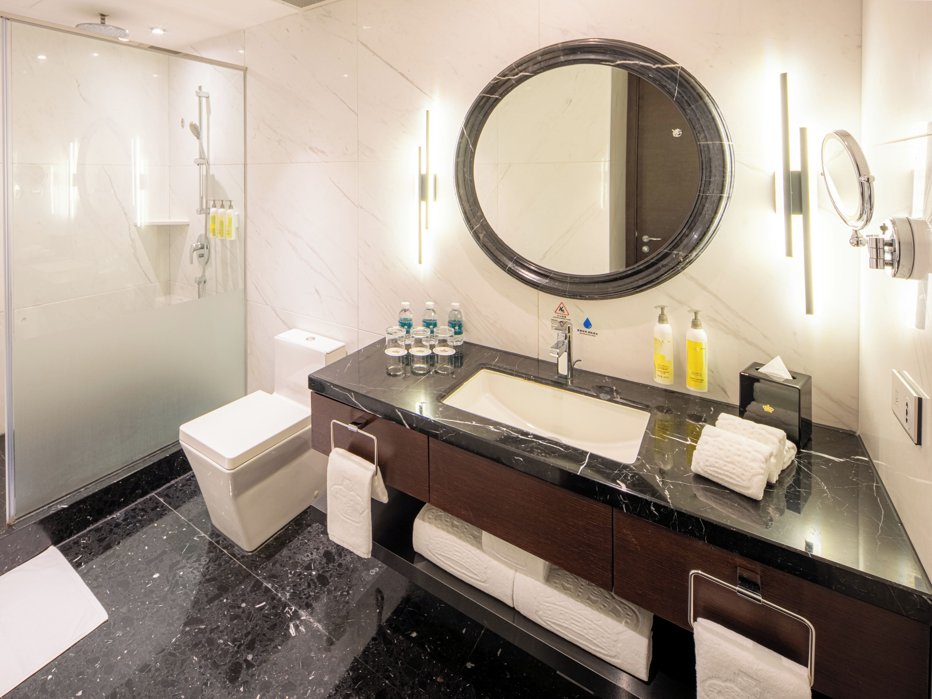 A modern bathroom with a marble vanity, a large mirror, and a glass-enclosed shower.