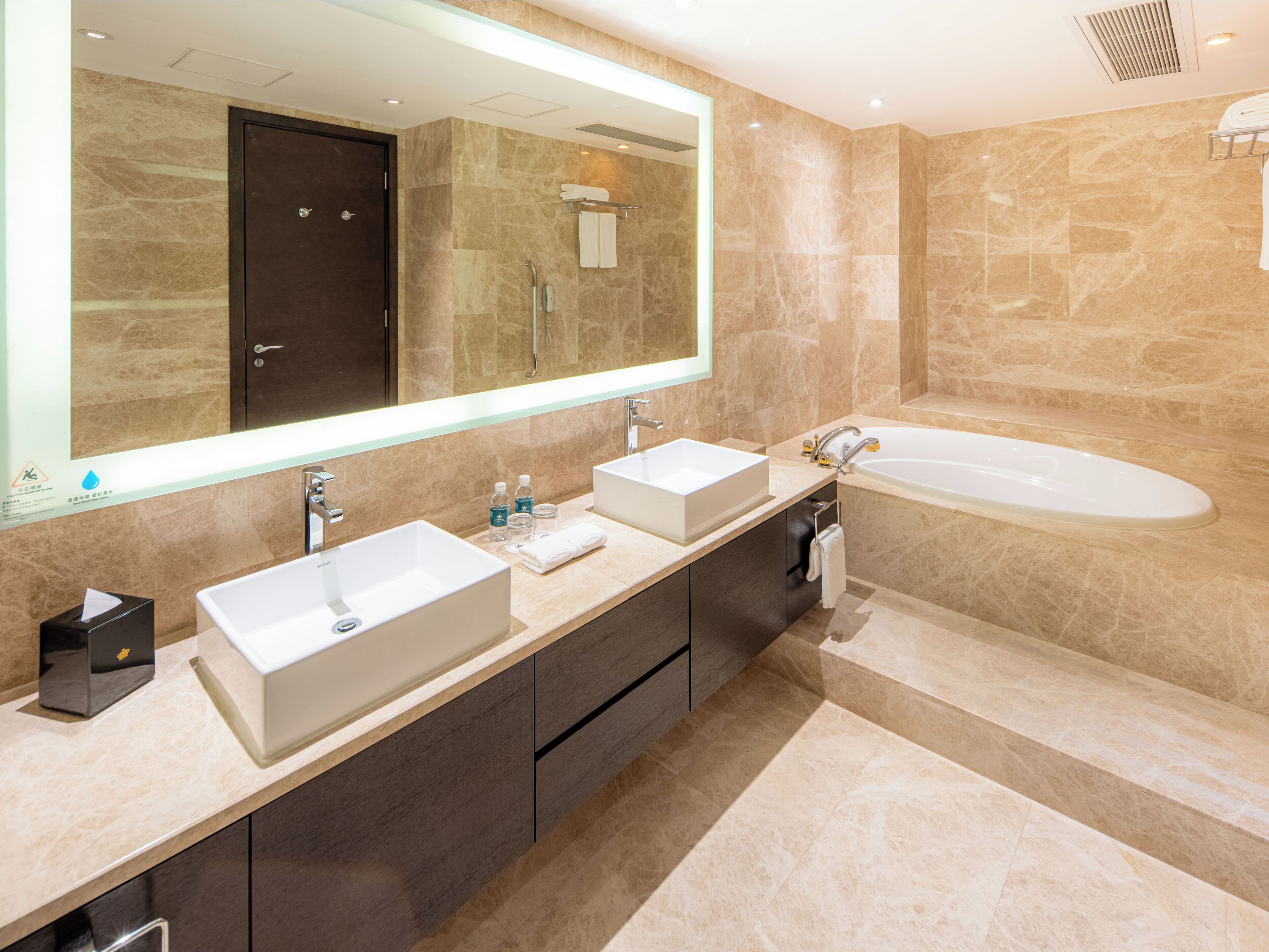A modern bathroom with two sinks, a large mirror, and a bathtub.