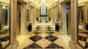 A grand hallway with marble floors, large columns, and a chandelier. - Grand Emperor Hotel  (Macau)