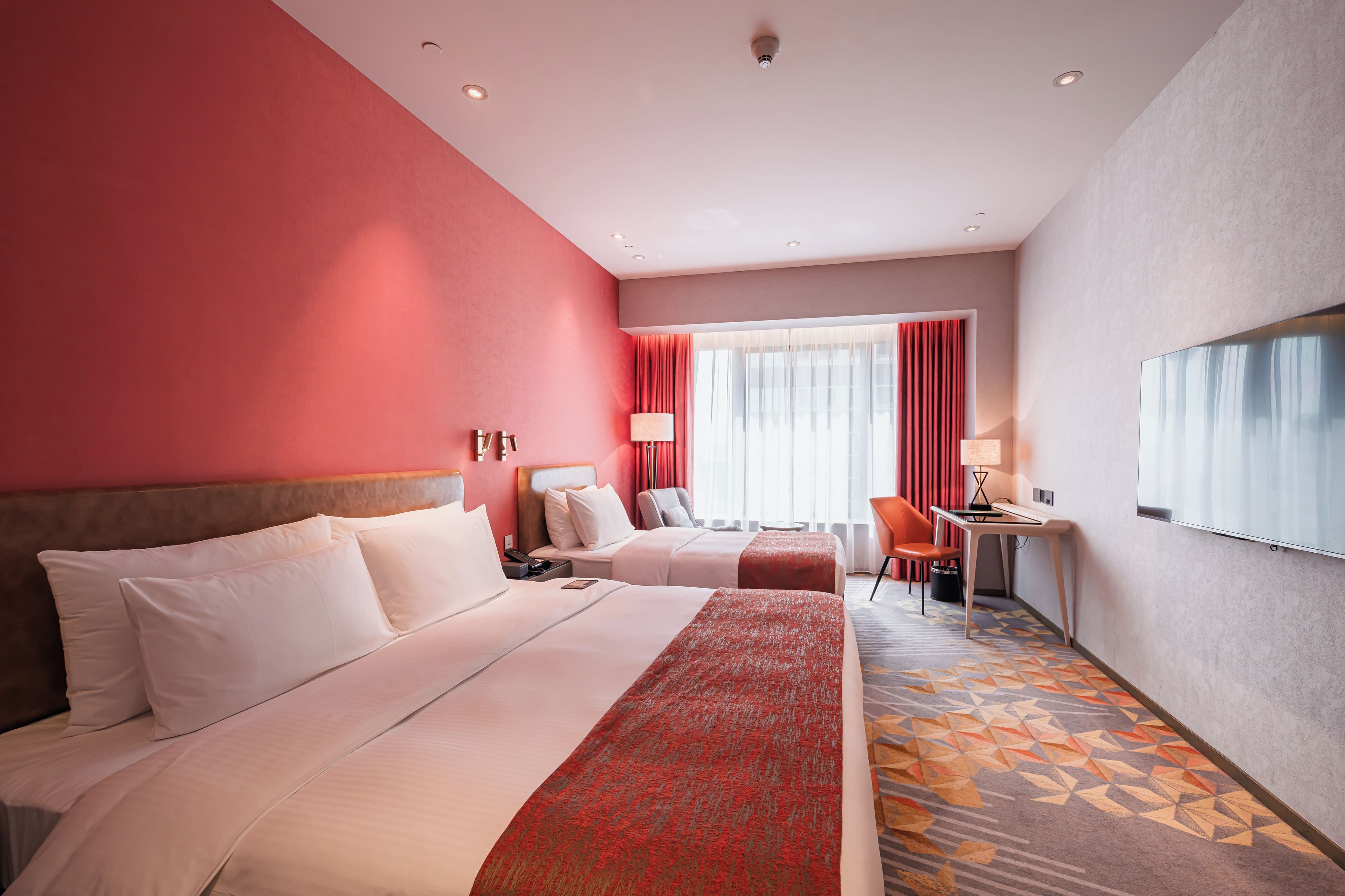 Ein Hotelzimmer mit zwei Betten, einem Schreibtisch und einem Stuhl.