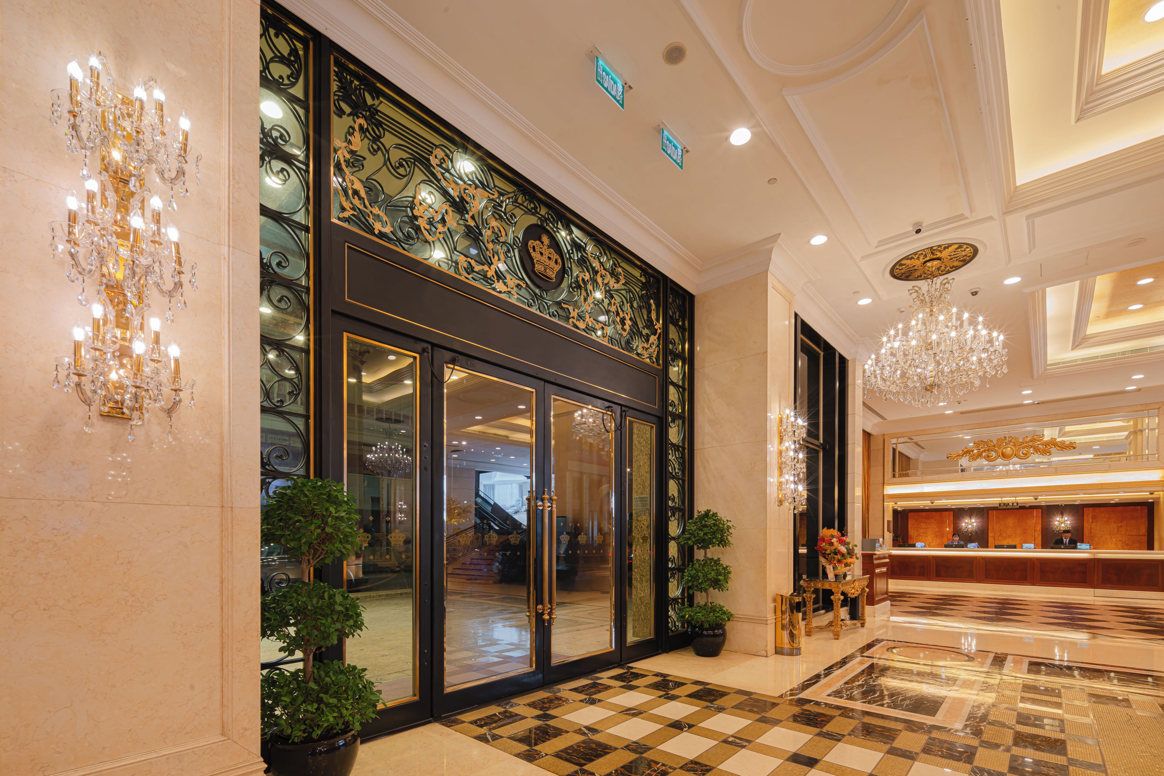 A lobby with a checkered floor, a reception desk, and a chandelier.